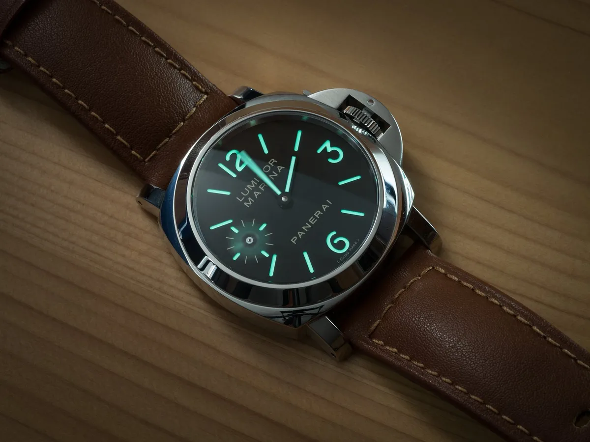 A Panerai Luminor with glowing lume on a brown leather strap